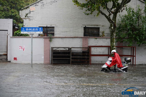 10月8日，上海市杨树浦路，一位市民推助动车走在积水中。赖鑫琳摄（来源：国际在线）