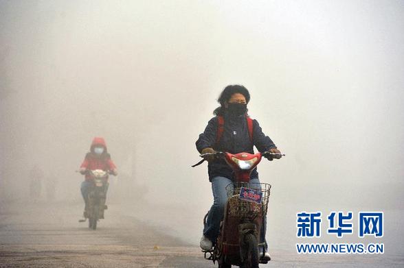 资料图片：12月7日，市民在雾霾笼罩下的南京街头骑行。 截止当日15时，南京实时空气质量指数AQI达到338，市民纷纷戴口罩出行。 新华社发