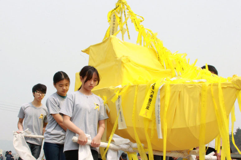 当地时间2015年4月15日，韩国珍岛，“世越号”沉船事故发生1周年的前一天，遇难者家属抬纸船举行慰灵祭。
