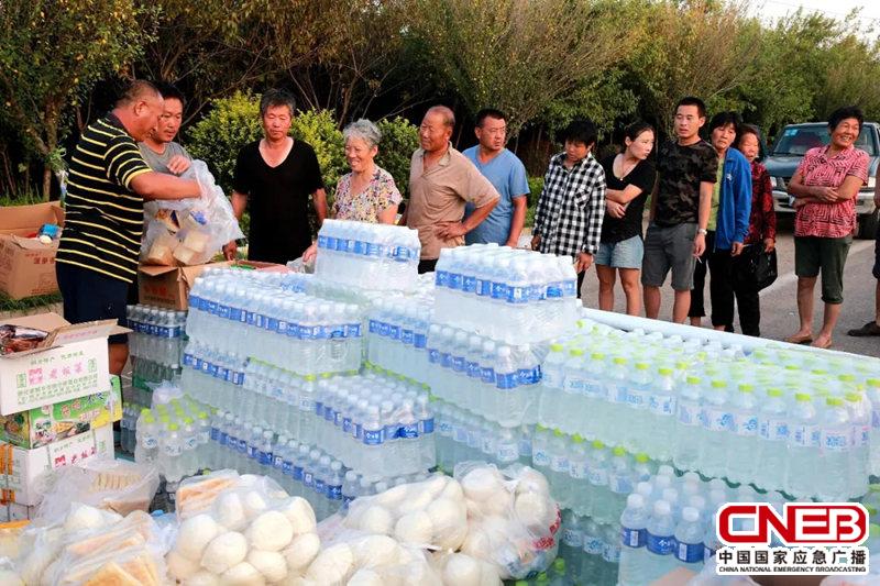 △8月24日，山东潍坊，志愿者在寿光市营里镇为民众免费发放物资。（图自视觉中国）