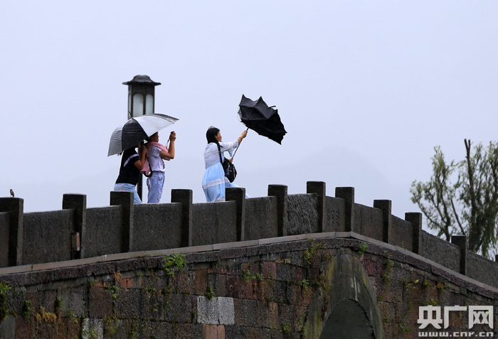 8月10日，在杭州西湖断桥上，一位游客的伞被风吹翻。（央广网记者 魏炜 摄）