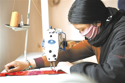 在青海省玉树藏族自治州加吉娘社区民族服饰加工车间，当地牧民索南看卓在缝制布饰（四月三日摄）。 新华社记者 张龙 摄